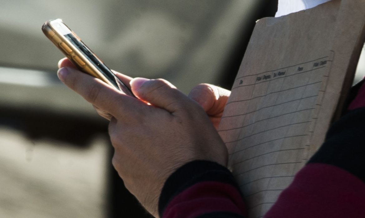 Pessoa consulta restituição do Imposto de Renda no celular, sem dados pessoais visíveis