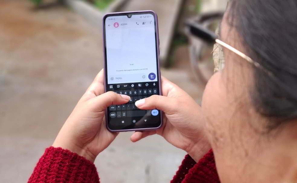 Mulher de costas digita mensagem de texto no celular