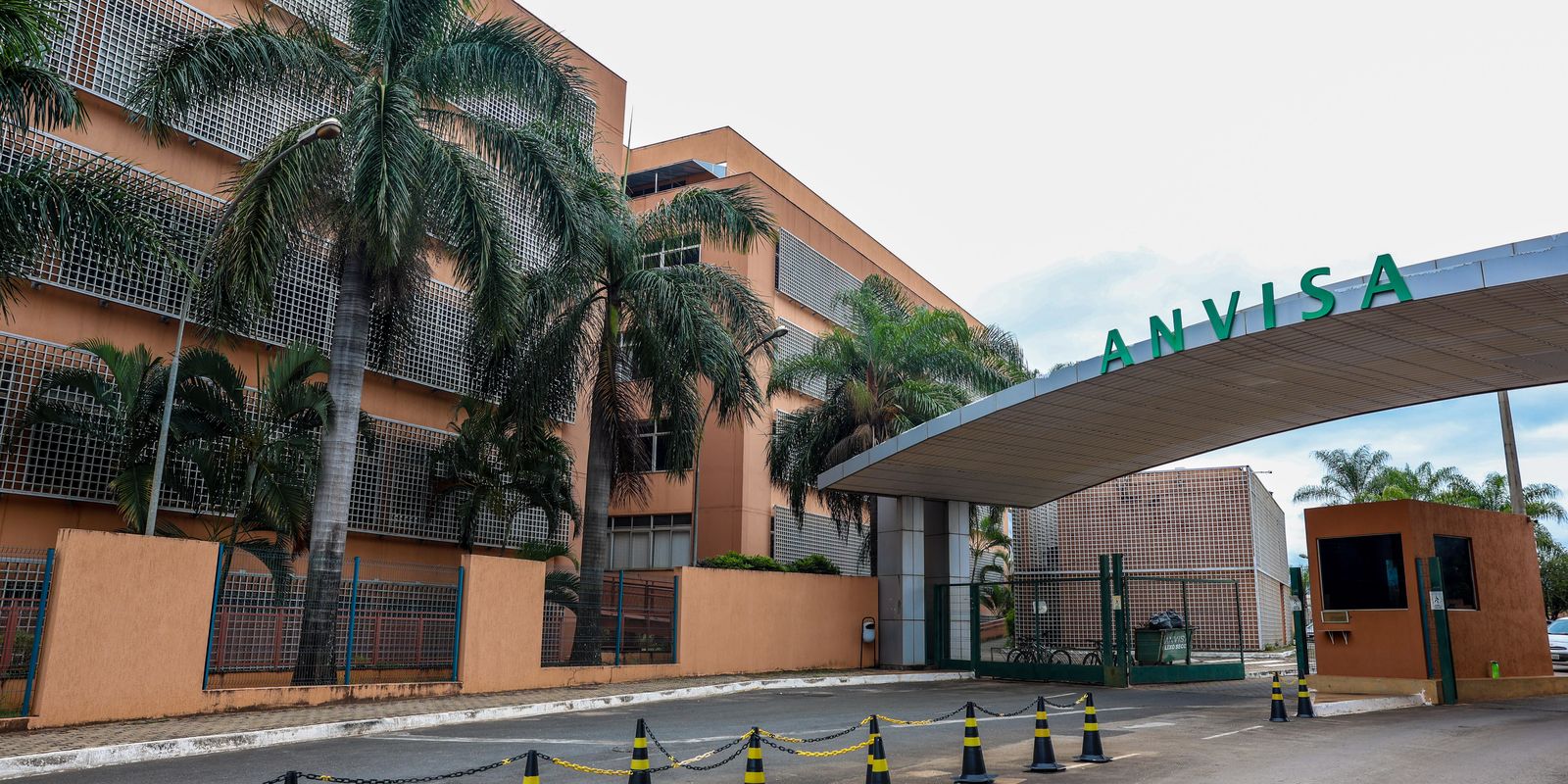Entrada da sede da Anvisa em Brasília, com letreiro verde e palmeiras