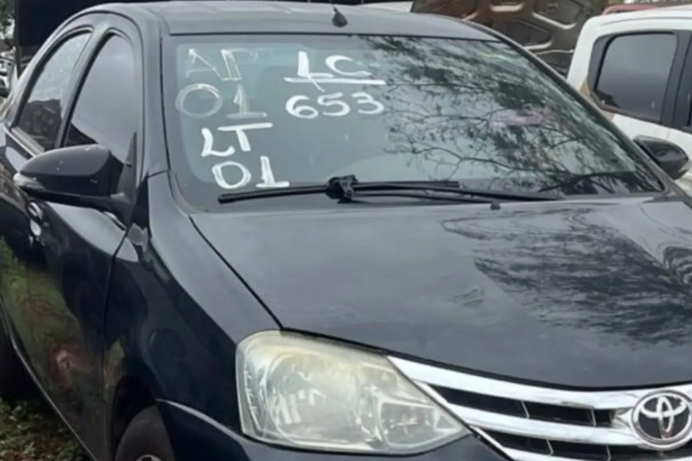 Sedã preto Toyota Etios estacionado em pátio, com «LT 01» e «653» escritos no para-brisa