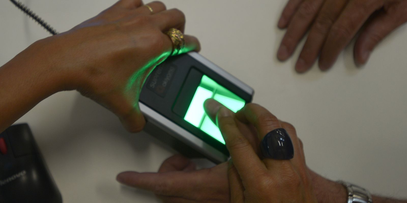 Dedo sobre leitor biométrico de impressão digital iluminado em verde