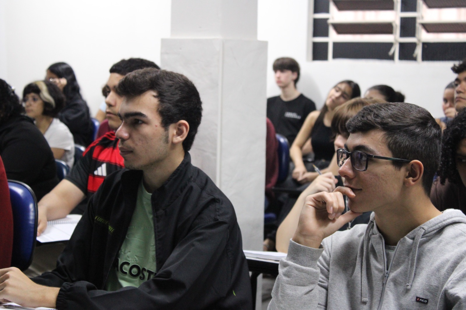 Jovens estudantes sentados em sala de aula prestando atenção à aula