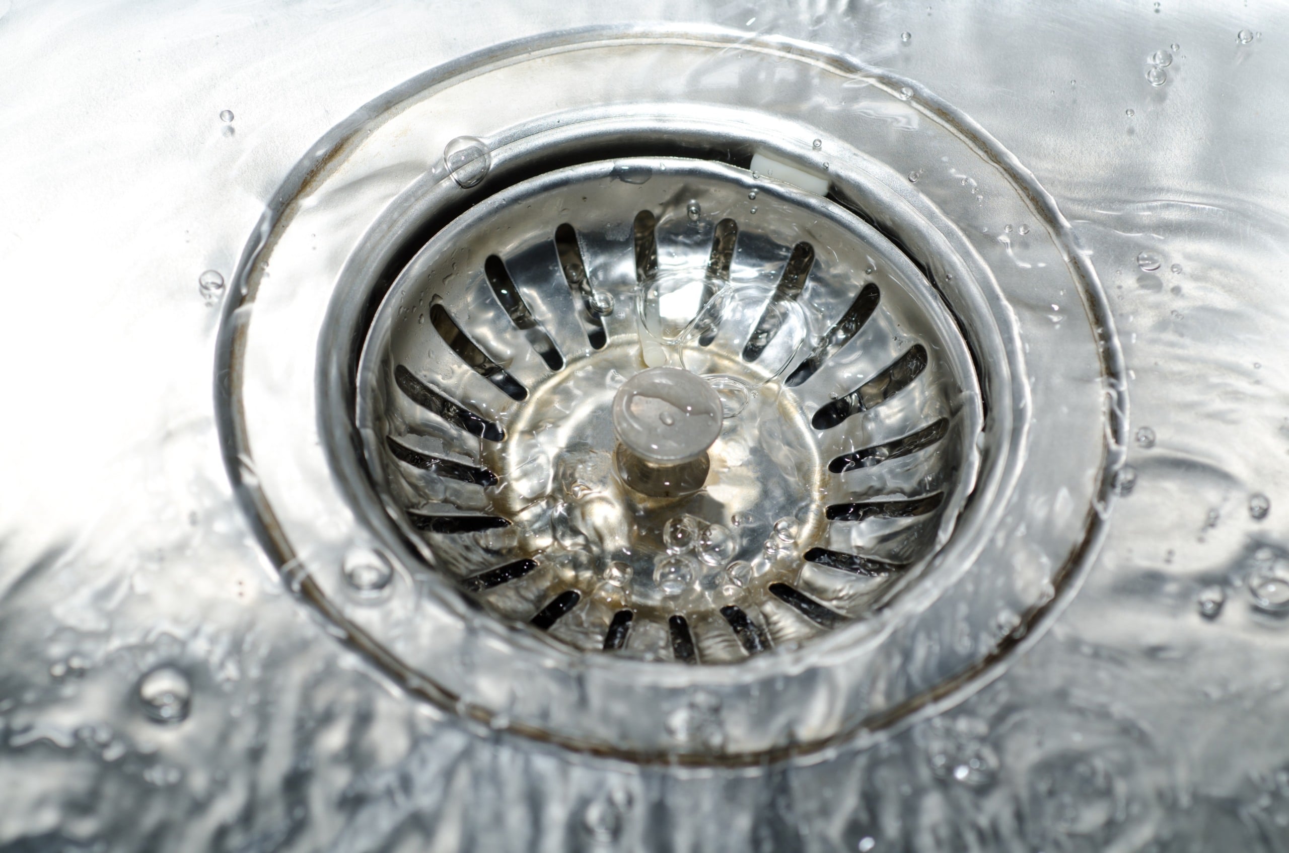 Água escoando por um ralo de aço inox, em close