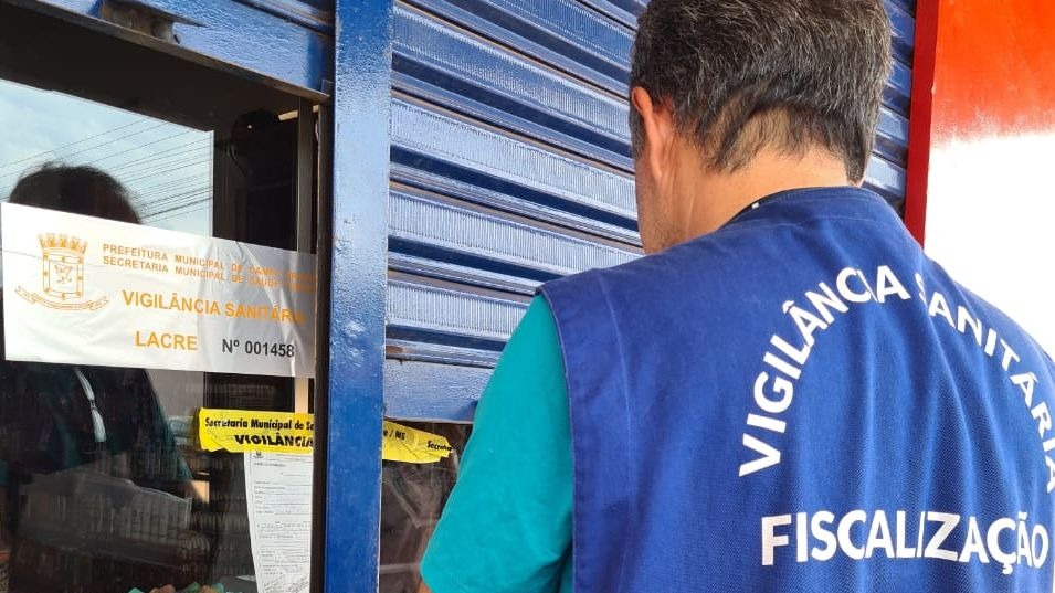 Fiscal com colete da Vigilância Sanitária de Campo Grande diante de estabelecimento