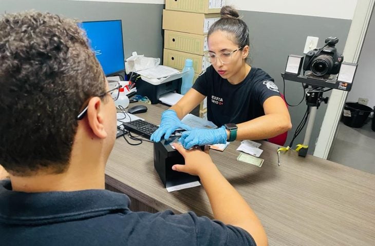 Servidora do Instituto de Identificação coleta digitais de um cidadão no balcão de atendimento