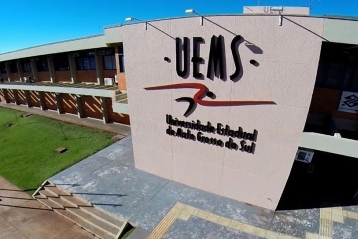 Fachada de prédio da UEMS com o nome Universidade Estadual de Mato Grosso do Sul, vista do alto em dia de céu azul