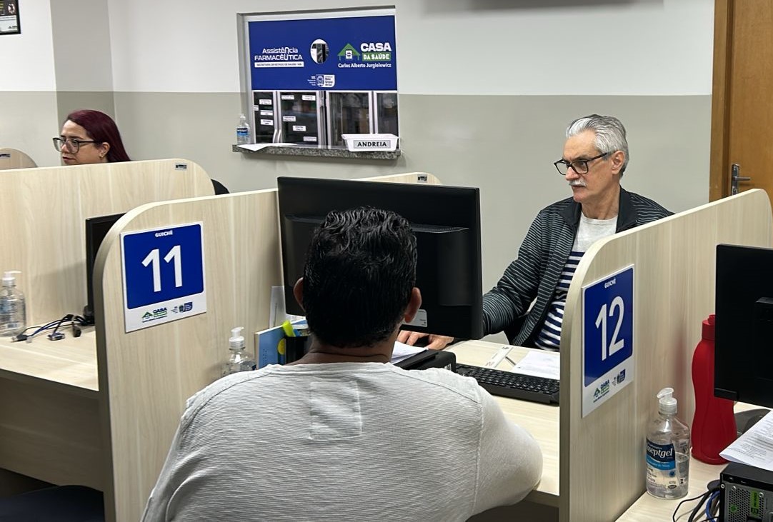 Guichês de atendimento da Casa da Saúde, com servidores e pacientes