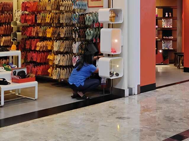 Funcionária organiza prateleira de calçados em loja de shopping