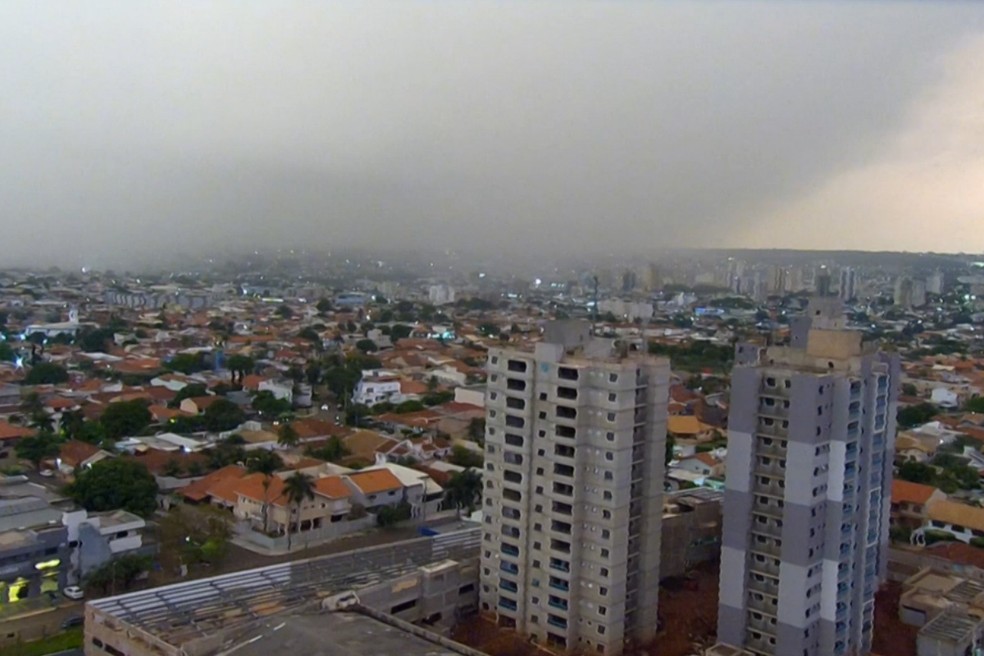 Vista aérea de Campo Grande com prédios e céu escuro de chuva ao fundo