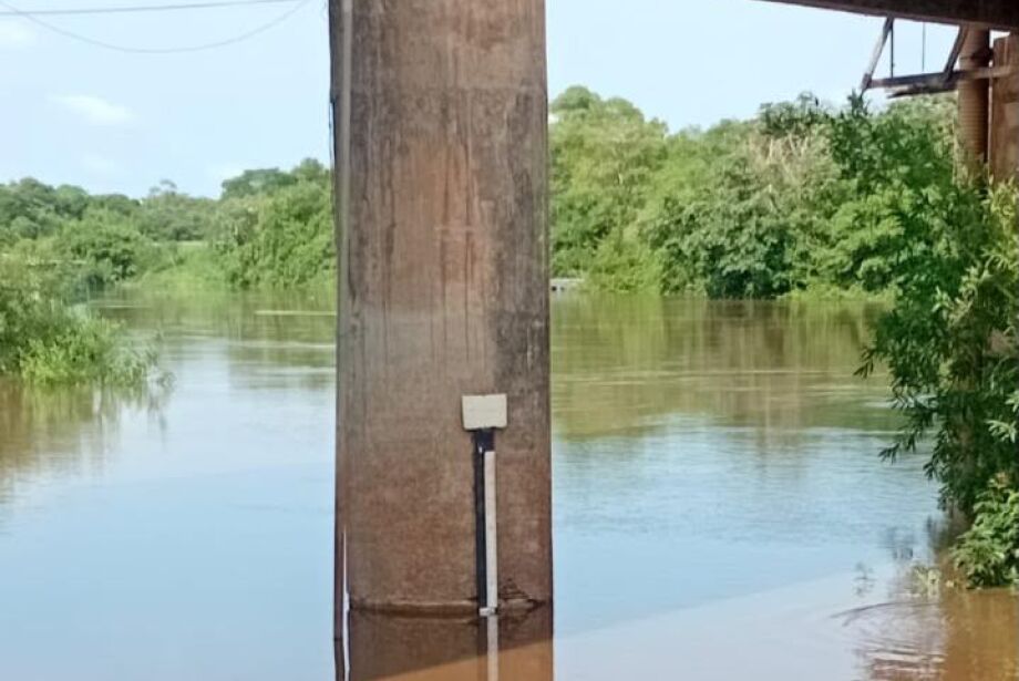 Pilar de ponte com régua de medição e o Rio Miranda cheio, cercado de vegetação