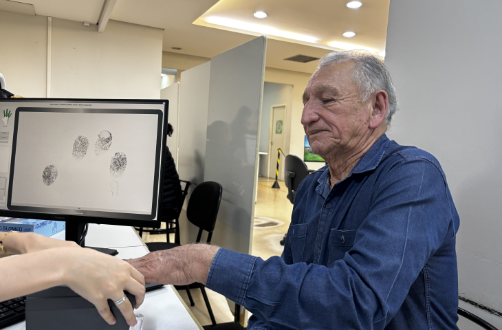 Homem idoso faz o cadastro de digitais em posto de identificação